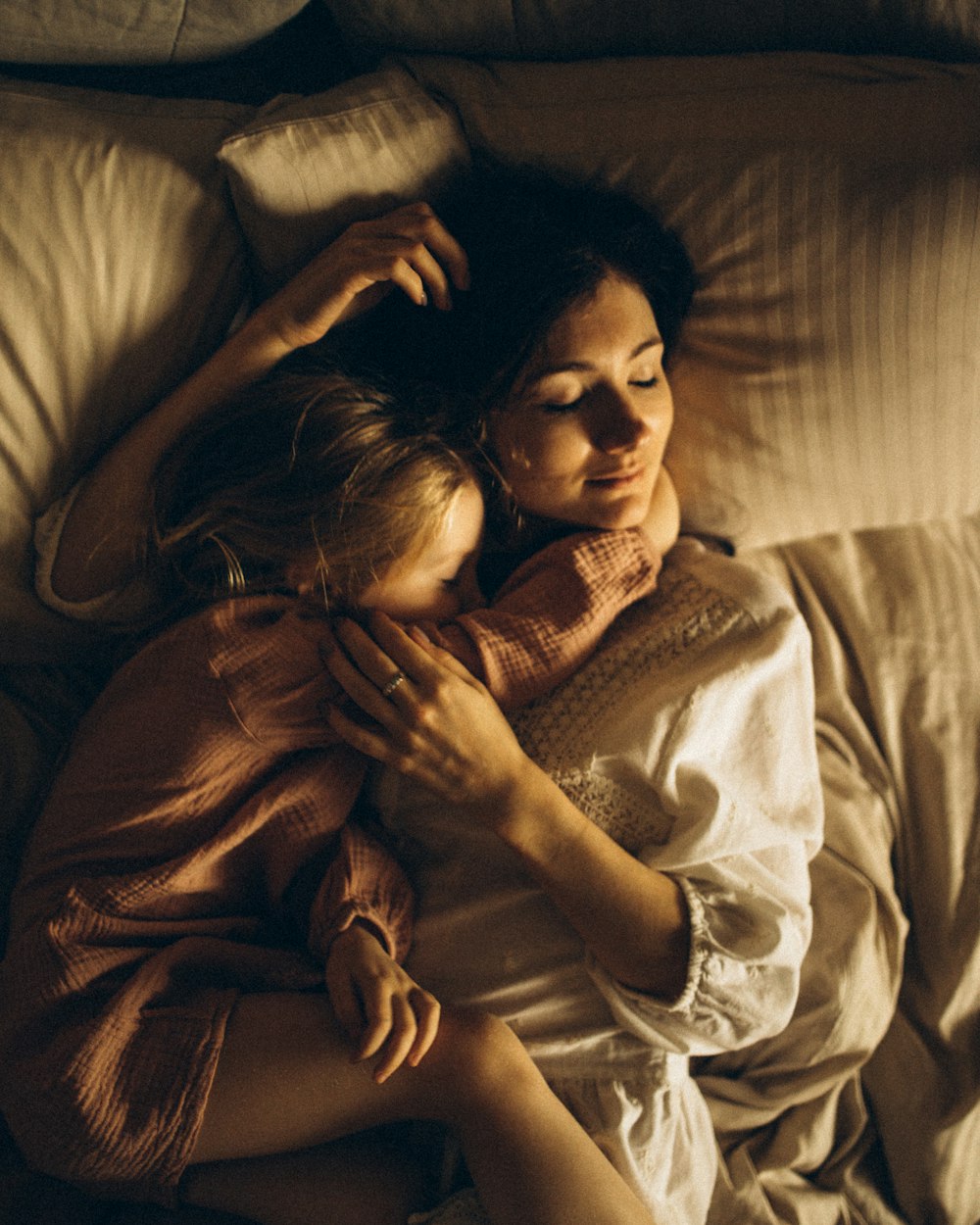 Une maman enlace tendrement sa fille sur son lit
